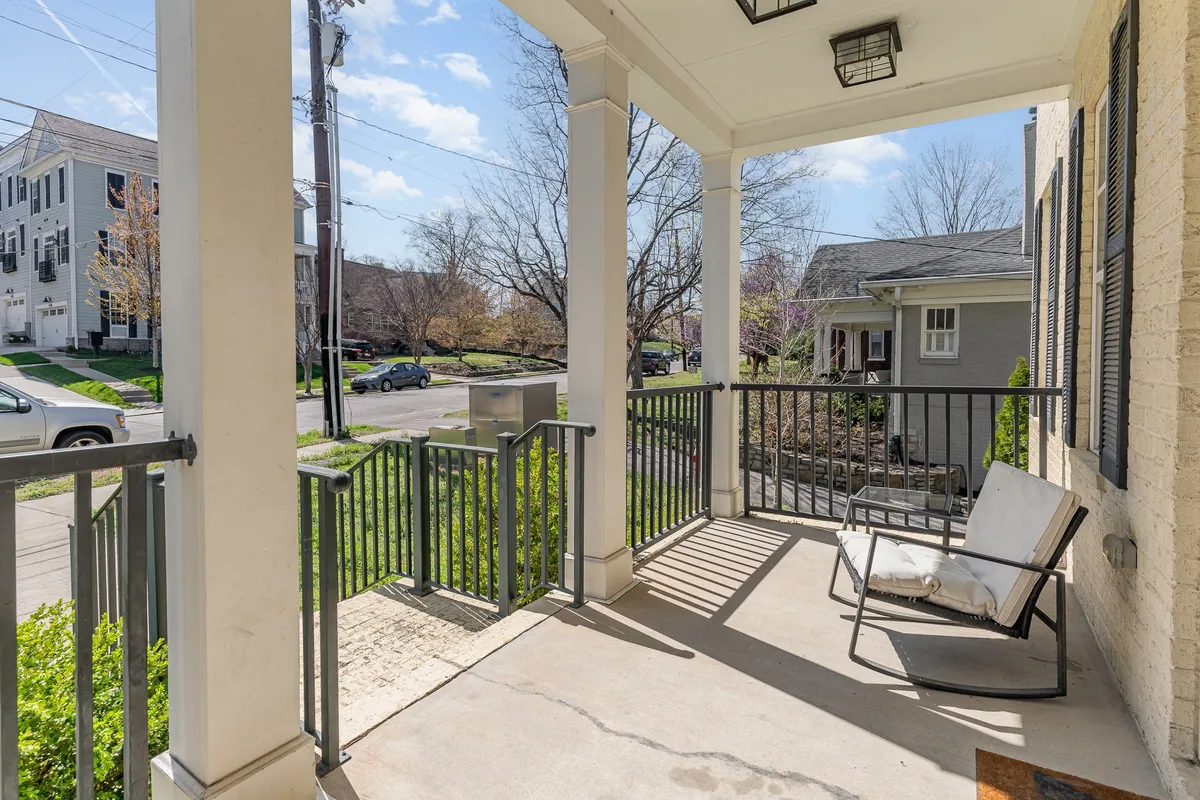 A tranquil front porch scene with a classic porch swing, railings, landscaped greenery, and views out to the street. The inviting setting highlights the relaxing and social potential of the porch for morning coffees, sunset chats, or simply enjoying the outdoor ambiance.