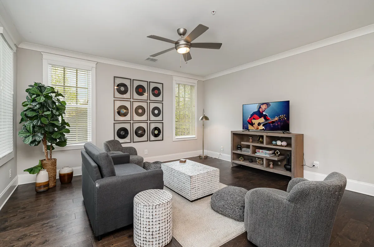 The image showcases a cozy, modern living area featuring a large television, stylish vinyl record wall art, plush seating arranged for conversation, and a vibrant potted plant, creating a welcoming space for relaxation and connection.